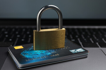 Cyber security. Metal padlock and credit cards on laptop, closeup