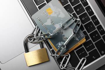 Cyber security. Metal padlock with chain and credit cards on laptop, top view