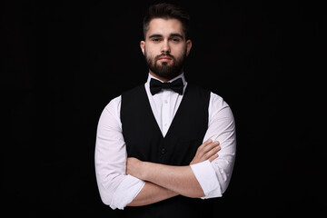 Portrait of handsome man in shirt and bow tie on black background