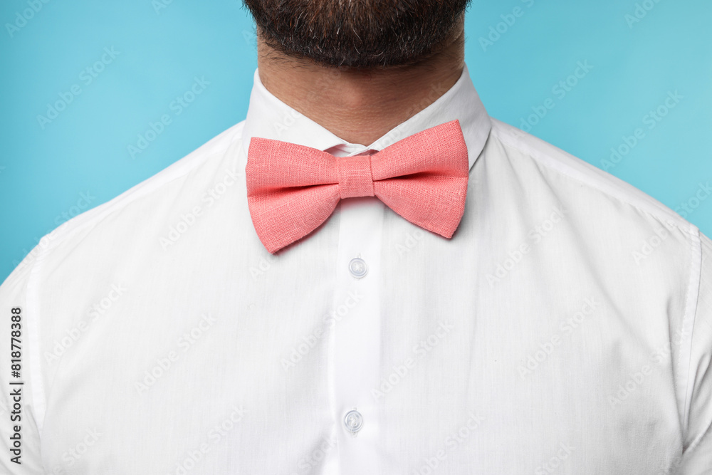 Wall mural man in shirt and bow tie on light blue background, closeup