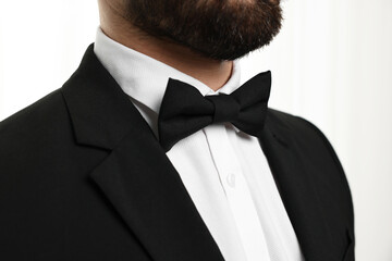 Man in suit, shirt and bow tie indoors, closeup