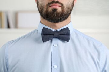 Man in shirt and bow tie indoors, closeup