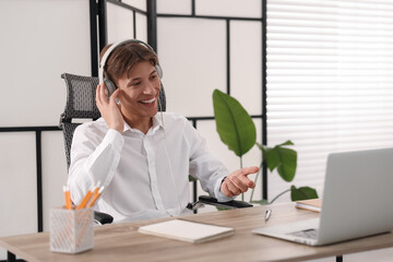 Man in headphones using video chat during webinar at wooden table in office
