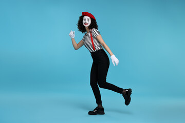 Funny mime with beret posing on light blue background