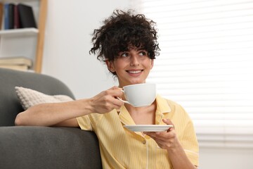 Beautiful young woman in stylish pyjama with cup of drink at home