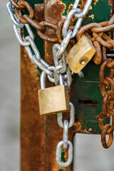 close up of padlock and chains wrapped around rusty gate with weathered paint