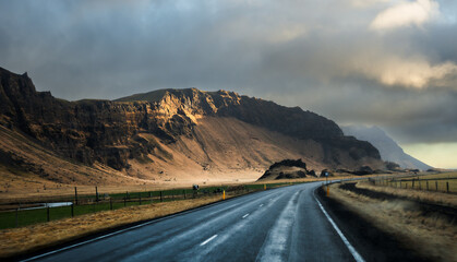 a car driving down the highway near mountains under storm clouds