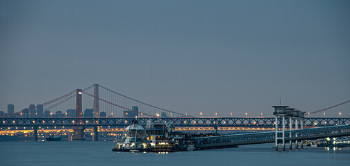 Massive vessel floating gracefully beside an architectural marvel in Wuhan