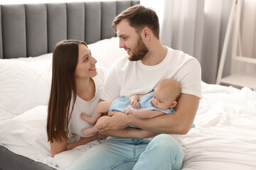 Fototapeta premium Happy family. Parents with their cute baby on bed indoors