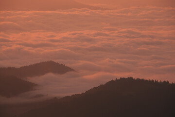View of hills hidden in the sea of clouds at sunset