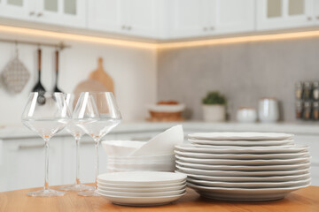 Clean plates, bowls and glasses on wooden table in kitchen