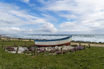 Un bateau reposant sur des galets sur un espace vert faisant face à l'océan dans la baie d'Audierne en Bretagne.