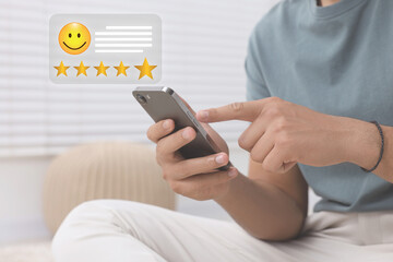 Man leaving service feedback with smartphone at home, closeup. Stars and emoticon over device