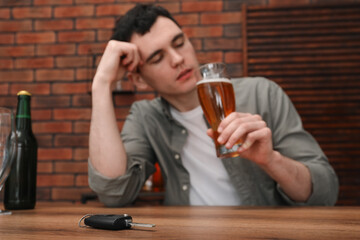 Man holding glass of alcoholic drink and sitting at table with car keys, selective focus. Don't...
