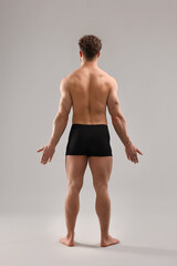 Man with muscular body on light grey background, back view