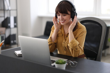 Woman in headphones watching webinar at table in office