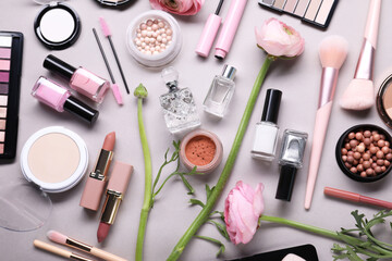 Flat lay composition with different makeup products and beautiful spring flowers on gray background