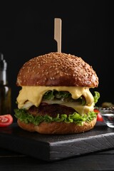 Vegetarian burger with delicious patty and cheese on black wooden table