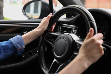 Woman holding steering wheel while driving her car, closeup