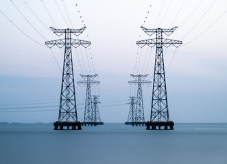 High voltage transmission towers over sea water, long exposure