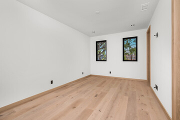 a large room with two windows, and a wood floor
