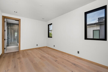 an empty room with wooden floor and window in the corner