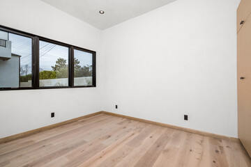 Fototapeta premium a white empty room with a window and wood floors in it