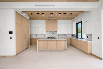 a large white kitchen with wood accents and a center island