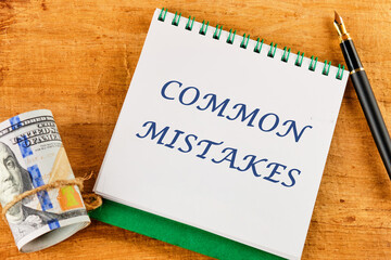 Common mistakes, text on a notepad near money and a fountain pen on an abstract background