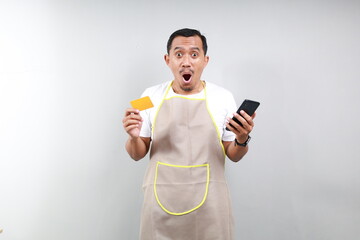 Shocked asian man barista bartender barman employee wearing brown apron white t-shirt work in...