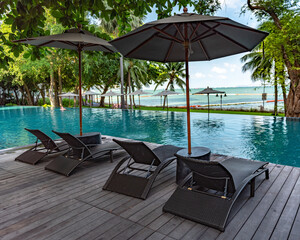 Fototapeta premium Poolside reclining chairs by the pool at the beach