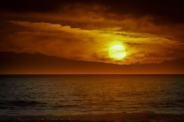 the sun is setting in a cloudy sky over the ocean