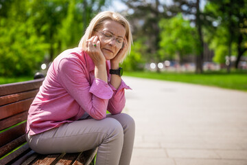 Portrait of mature woman in park. She is having headache.