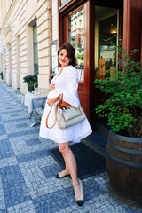 pregnant woman in white dress walk in the city