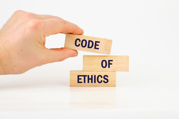 Organizational concept. CODE OF ETHICS is written on wooden blocks it is laid out by hand on wooden...