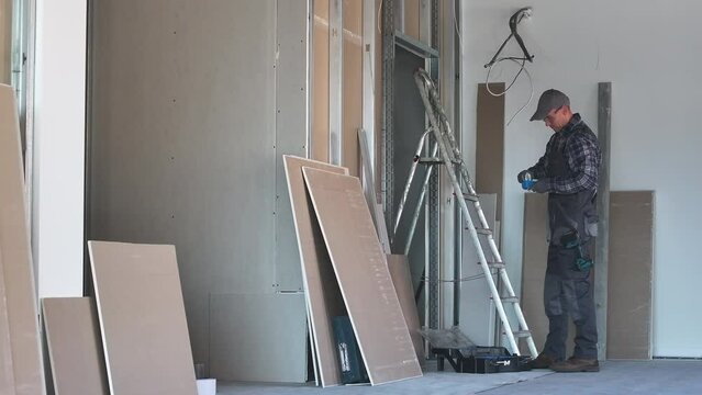 Construction Site Worker Building New Interior Drywall Made Walls.