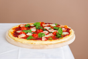 Fresh pizza, handmade, DIY pizza with ham, tomatoes, mozzarella and green on a table. Homemade pizza, yeast-free dough.