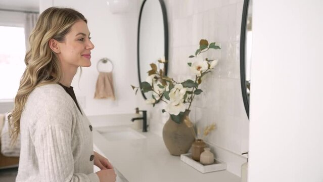 Caucasian female model drying her hands with towel and then fixing her hair in mirror