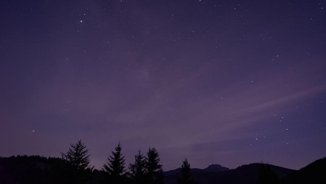 Night sky, disappearing under high clouds, silhouette of hilly forest landscape