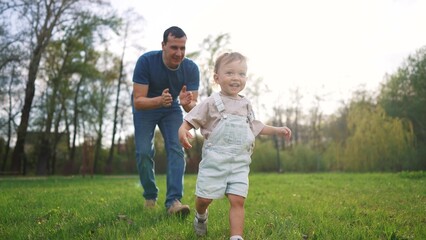 baby toddler and father run play in the park. happy family kid dream concept. baby and father...