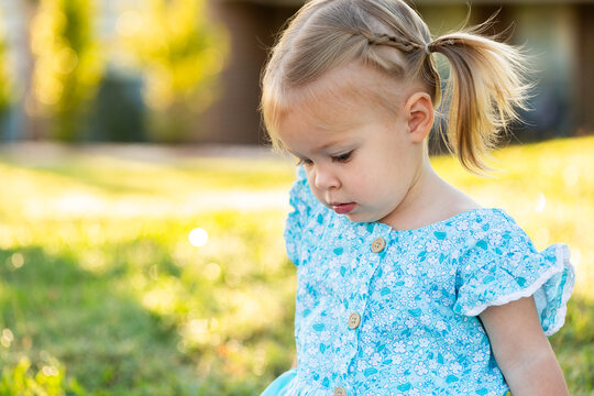 Portrait of a young girl in blue dress and pigtails looking sad