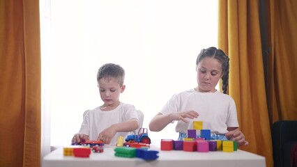 children toddler a group play with toys cars blocks. development fine motor skills kindergarten sunset concept. children group playing cubes on table near window. children play with blocks