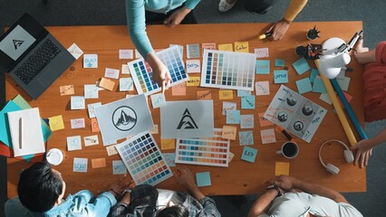 Top view of business team write graphic logo on meeting table with colorful sticky notes and design...