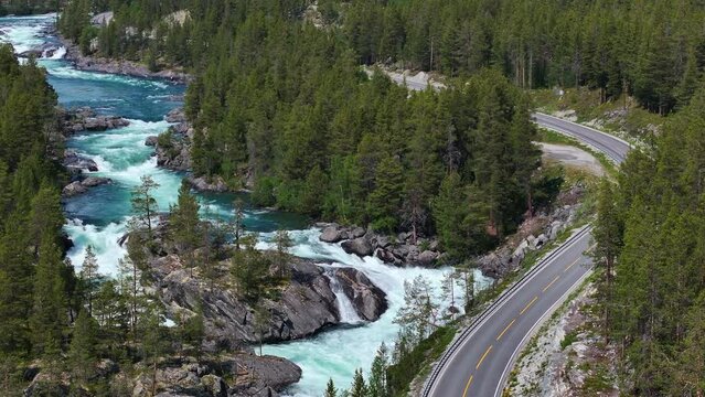 A River Flowing Through a Green Forest Next to Highway in Norway