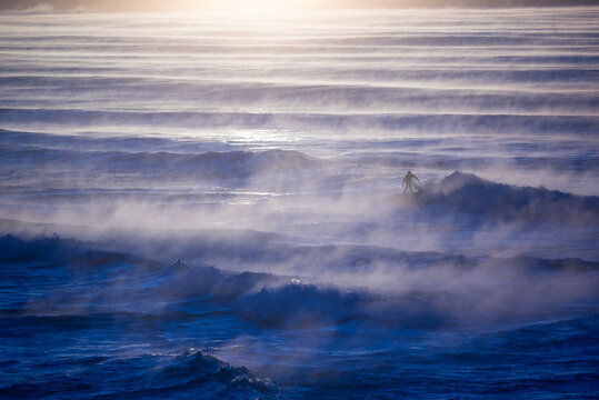 Lone surfer on waves with sea mist