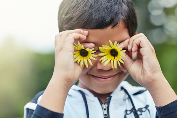 Boy, happy and flower eyes outdoor in nature for playing game, creativity and social development....