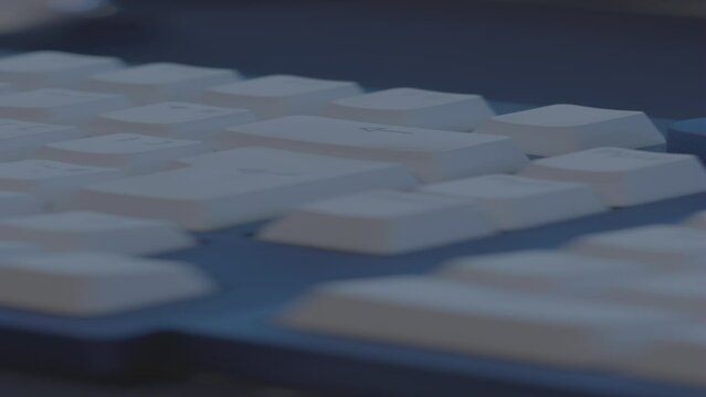 Closeup of an adult hand pressing backspace button on a blue-and white keyboard with blur background