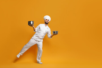 Professional chef with cooking pots on yellow background. Space for text