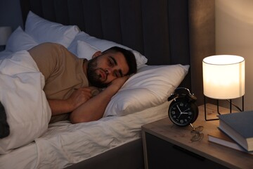 Frustrated man suffering from insomnia in bed