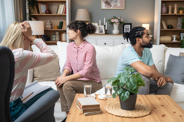 Serious young man and woman talking to psychologist counselor complain on bad relationship difficulties between husband and wife. Family couple counseling, conversation about problem, therapy session.